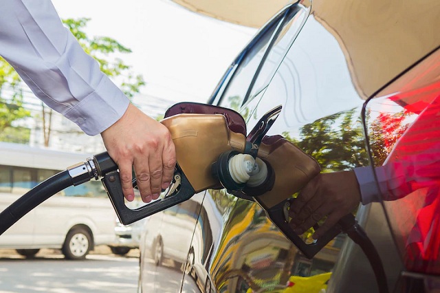 homme mettant de l'essence dans sa voiture dans une station d'essence